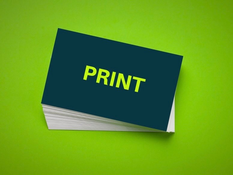 A stack of freshly printed navy business cards on a bright green background